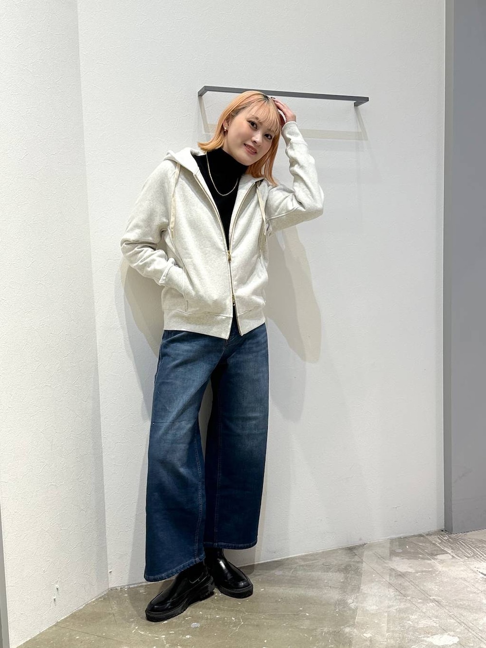 ブルー系のデニムパンツ、ホワイト系のパーカー、ブラック系のニット/セーターを着用したレディースの冬コーディネートの1枚目の写真