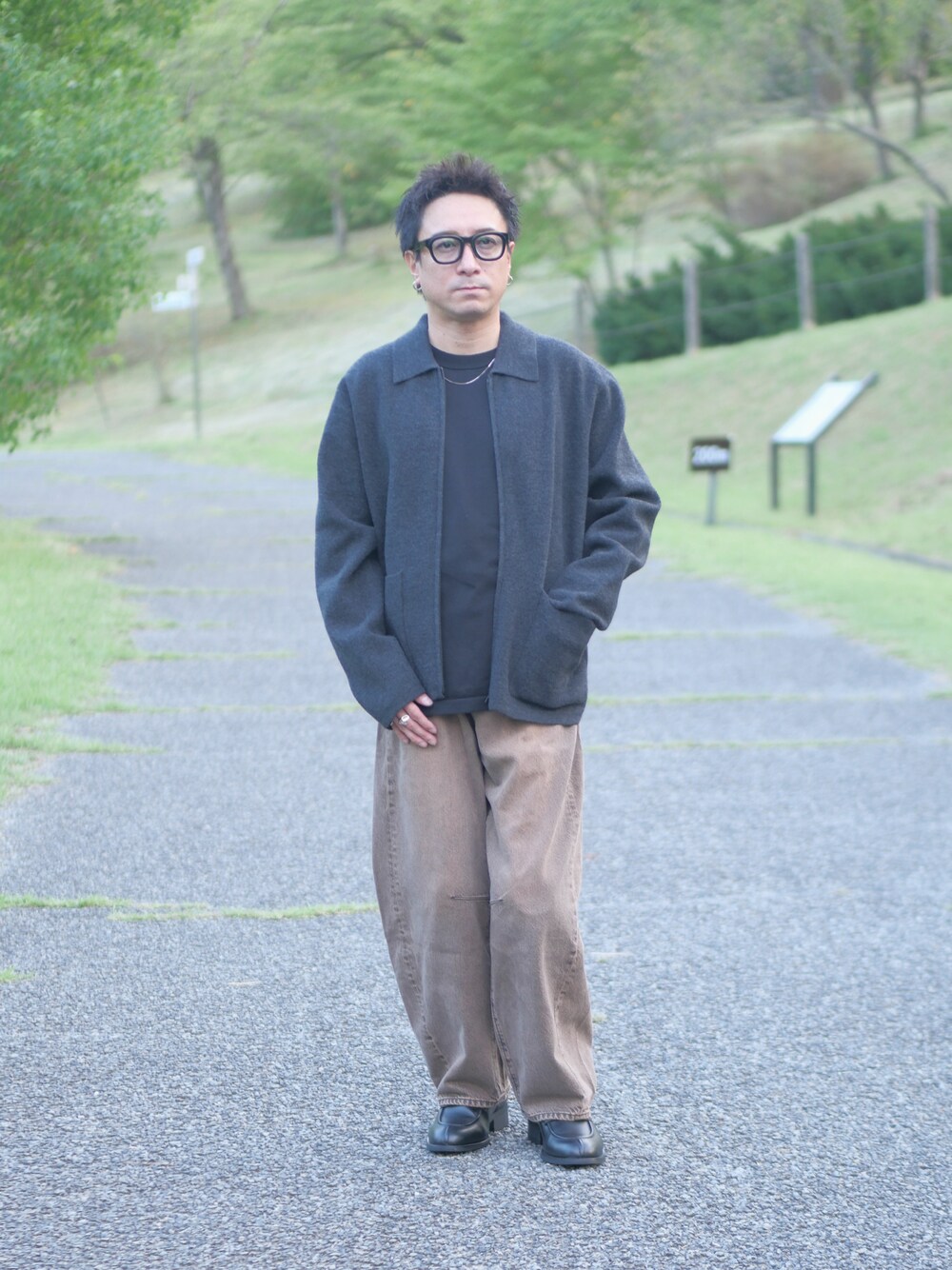 グレー系のブルゾン、ブラック系のニット/セーター、ブラウン系のデニムパンツを着用したメンズの秋コーディネートの1枚目の写真