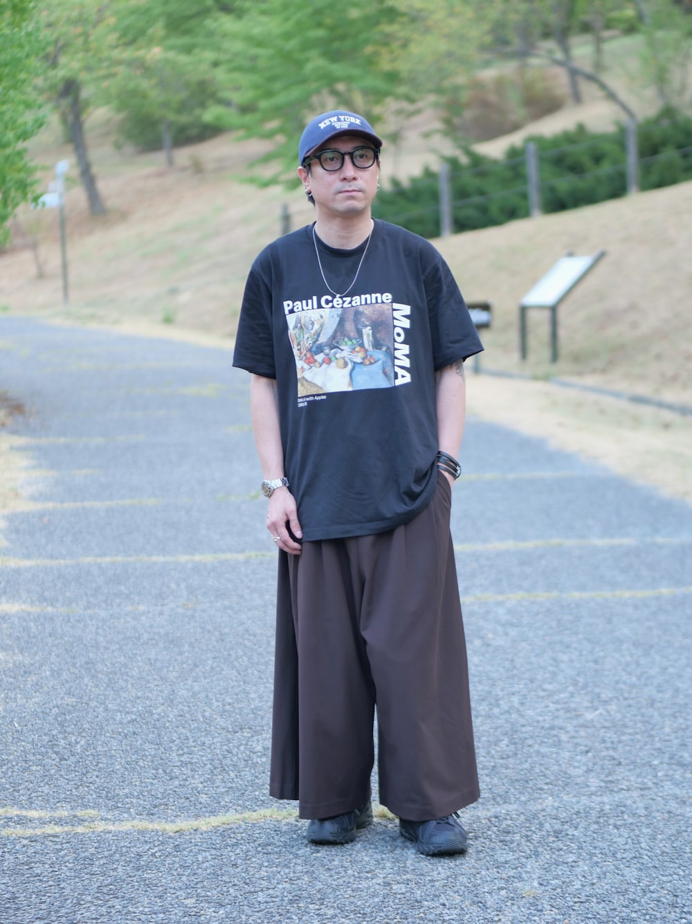 ブラック系のTシャツ/カットソー、ブラウン系のその他パンツ、ブラック系のスニーカーを着用したメンズの夏コーディネートの1枚目の写真