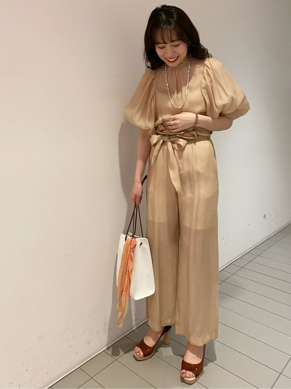 ブラウン系のパンプス、ホワイト系のハンドバッグ、ベージュ系のシャツ/ブラウスを着用したレディースの春コーディネートの1枚目の写真