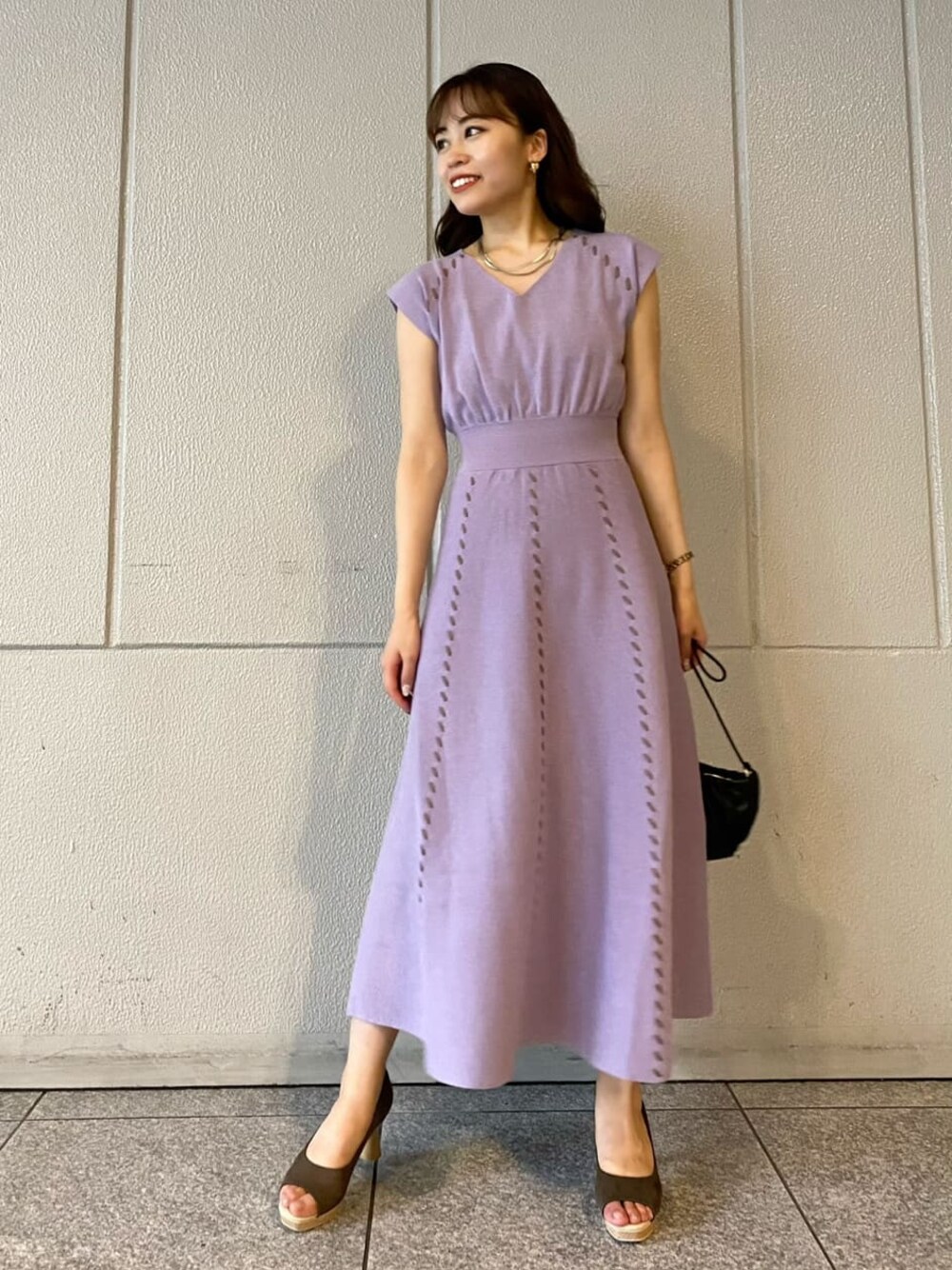 ブラウン系のパンプス、ブラック系のハンドバッグ、パープル系のワンピースを着用したレディースの夏コーディネートの1枚目の写真