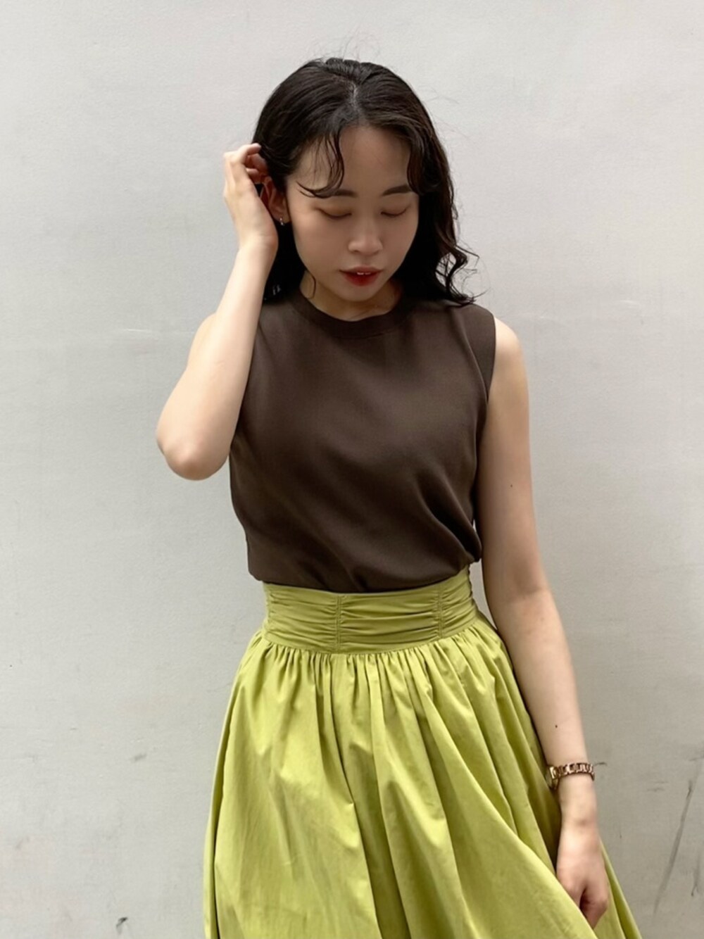 ブラウン系のニット/セーター、グリーン系のスカートを着用したレディースの夏コーディネートの1枚目の写真