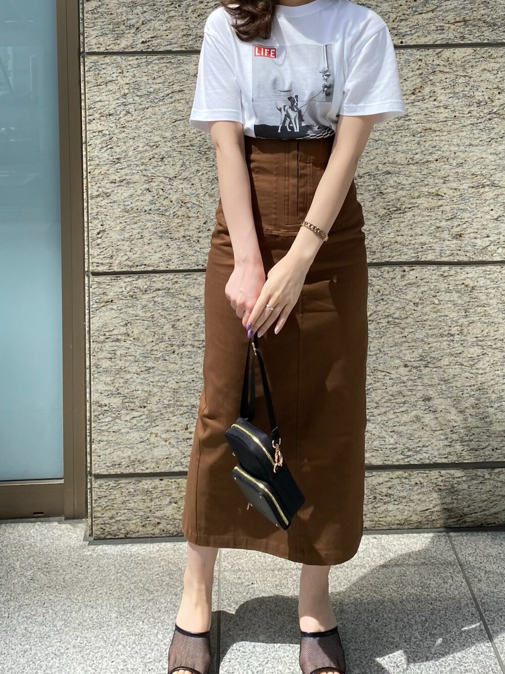 ブラウン系のスカート、ブラック系のその他シューズ、ホワイト系のTシャツ/カットソーを着用したレディースの春コーディネートの1枚目の写真