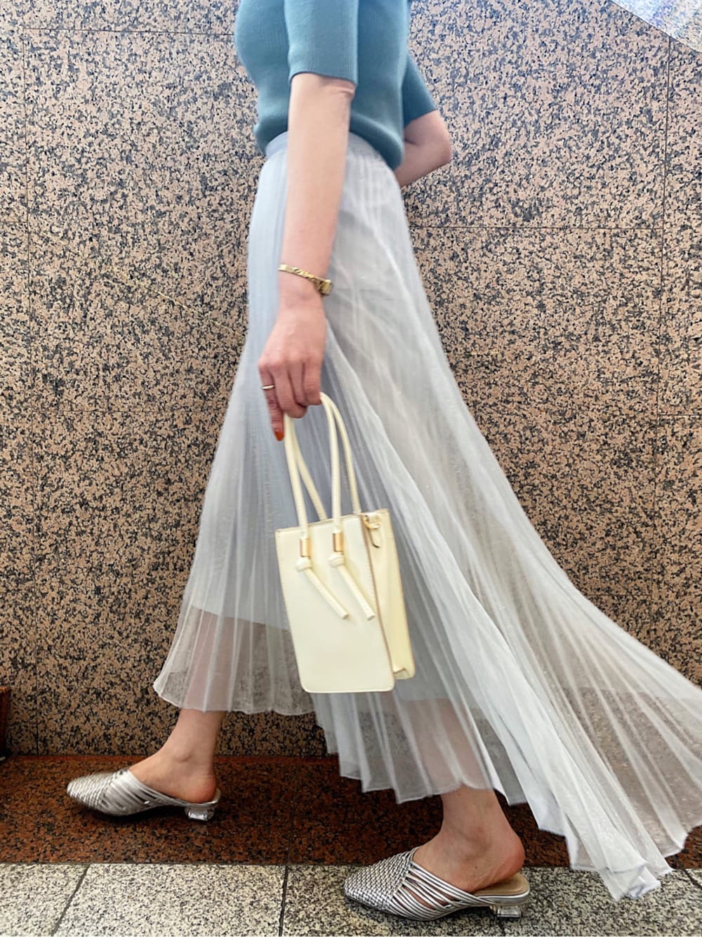 シルバー系のサンダル、シルバー系のスカート、ホワイト系のハンドバッグを着用したレディースの春コーディネートの1枚目の写真