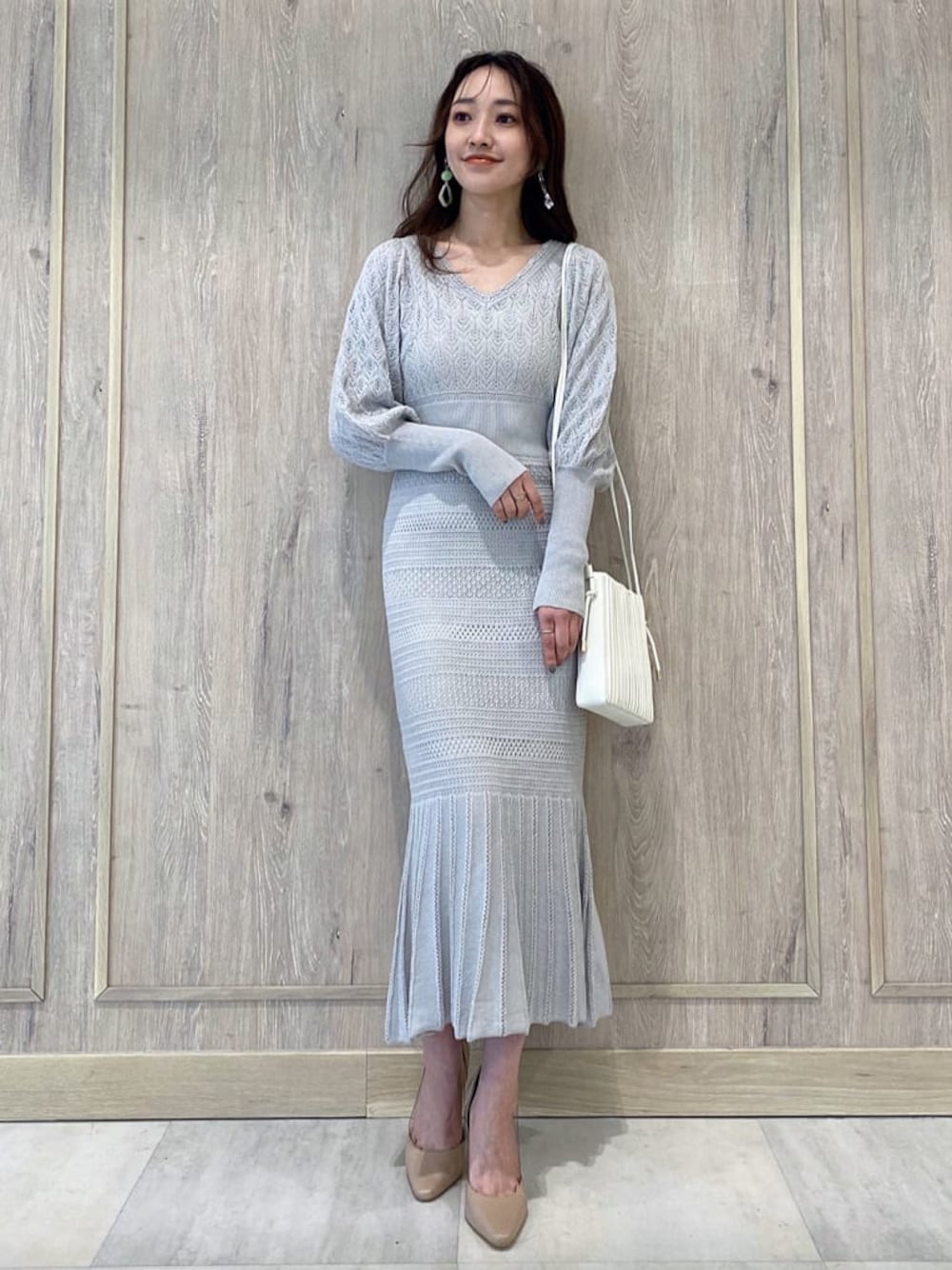 ベージュ系のパンプス、グレー系のワンピース、ホワイト系のハンドバッグを着用したレディースの冬コーディネートの1枚目の写真