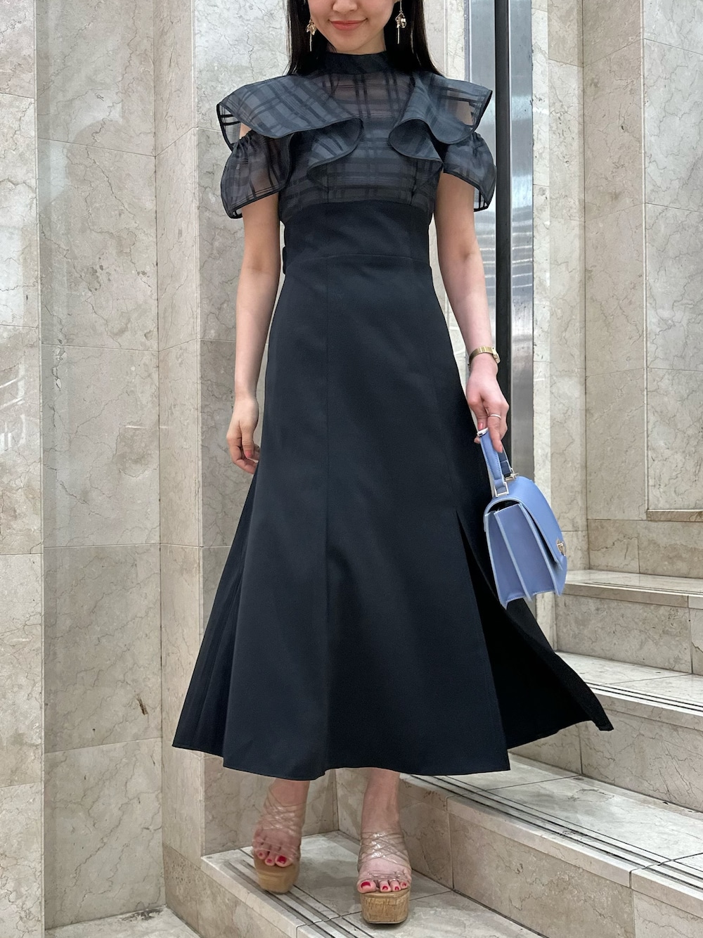 ブラック系のワンピース、ブルー系のハンドバッグ、その他のサンダルを着用したレディースの春コーディネートの1枚目の写真