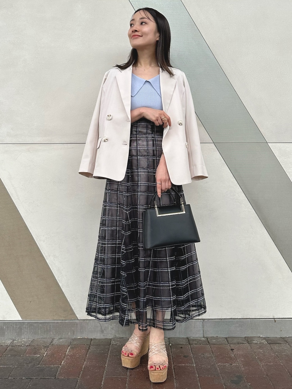 ブラック系のハンドバッグ、ブラック系のスカート、その他のサンダルを着用したレディースの春コーディネートの1枚目の写真