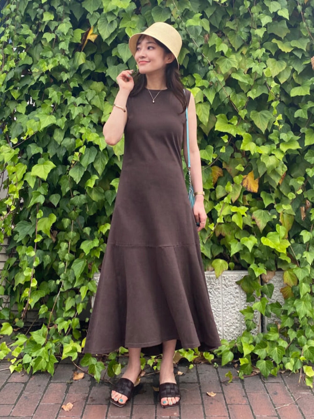 グリーン系のショルダーバッグ、ブラウン系のサンダル、ベージュ系のキャミソールを着用したレディースの夏コーディネートの1枚目の写真