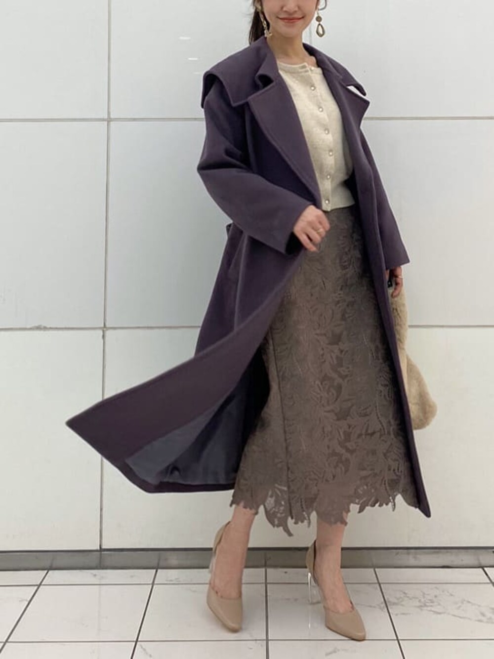 ベージュ系のパンプス、パープル系のチェスターコート、ホワイト系のニット/セーターを着用したレディースの冬コーディネートの1枚目の写真