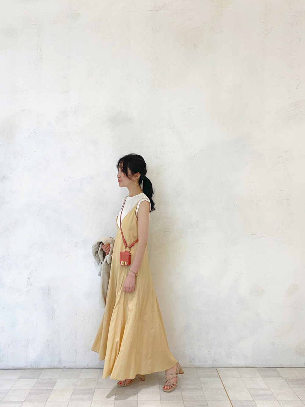 イエロー系のワンピース、ベージュ系のニット/セーター、ホワイト系のテーラードジャケットを着用したレディースの春コーディネートの1枚目の写真