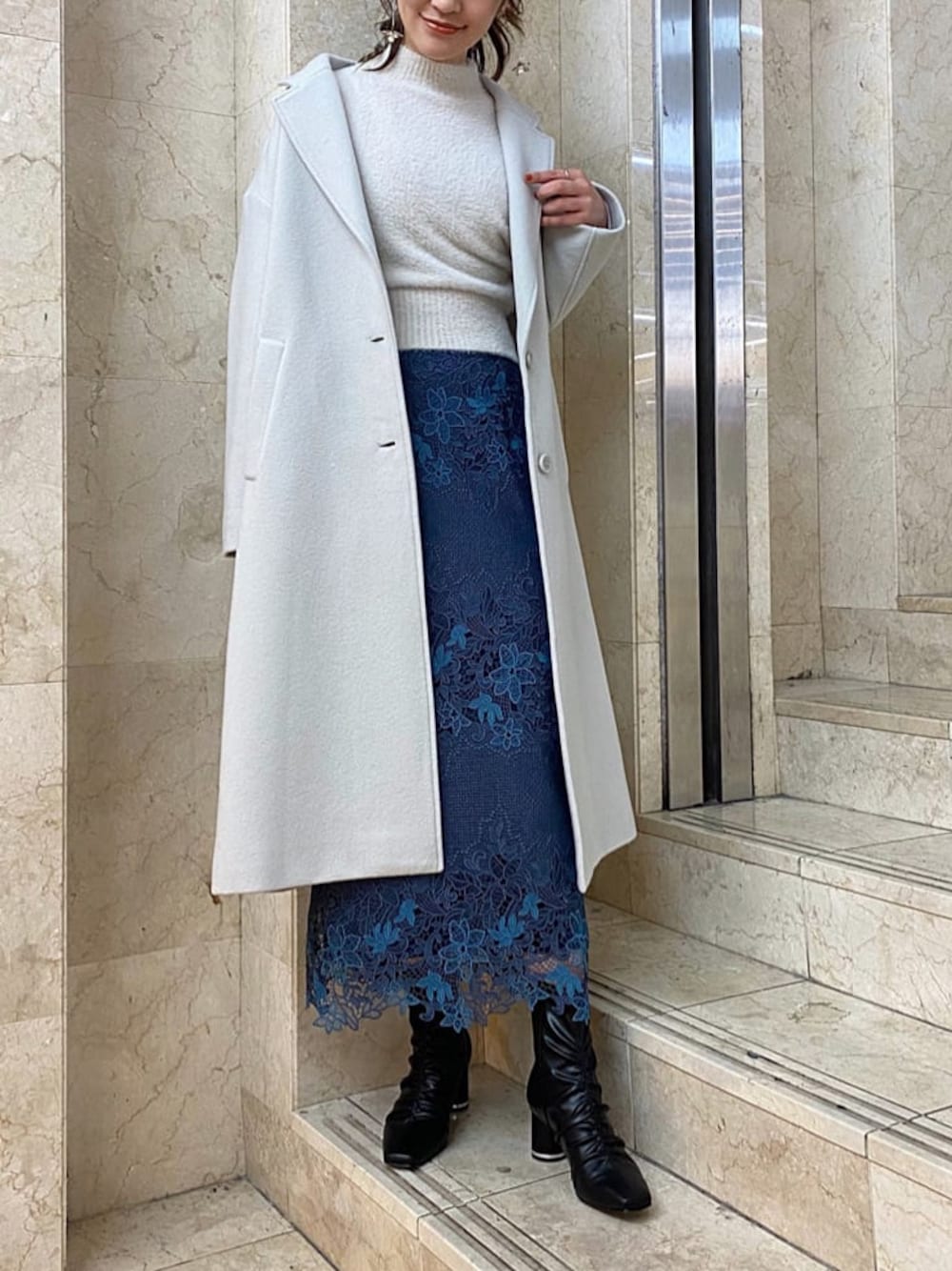 グリーン系のチェスターコート、ブルー系のスカート、ブラック系のその他シューズを着用したレディースの秋コーディネートの1枚目の写真