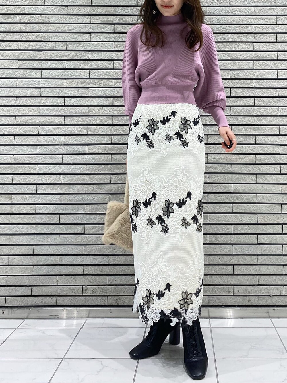 ホワイト系のスカート、ブラック系のブーツ、ピンク系のニット/セーターを着用したレディースの冬コーディネートの1枚目の写真