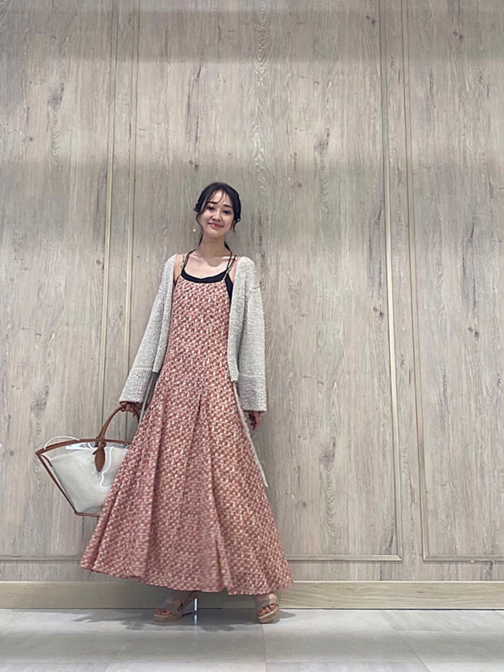 ブラウン系のトートバッグ、ベージュ系のカーディガン/ボレロ、オレンジ系のワンピースを着用したレディースの春コーディネートの1枚目の写真