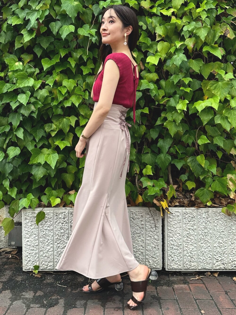 ブラウン系のサンダル、レッド系のニット/セーター、ピンク系のスカートを着用したレディースの夏コーディネートの1枚目の写真