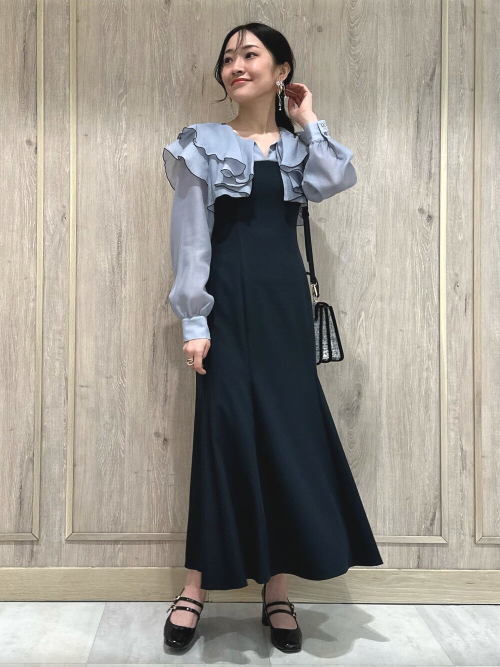 ブラック系のショルダーバッグ、グレー系のワンピース、ブラウン系のパンプスを着用したレディースの冬コーディネートの1枚目の写真