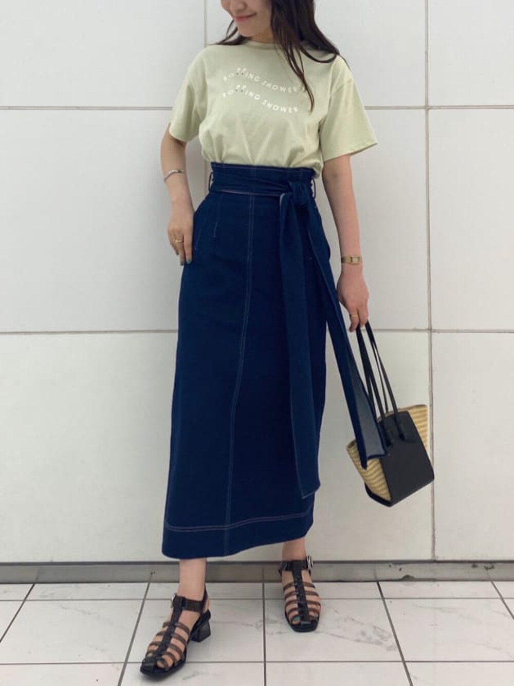 ブラック系のサンダル、ブラック系のトートバッグ、ブルー系のスカートを着用したレディースの夏コーディネートの1枚目の写真