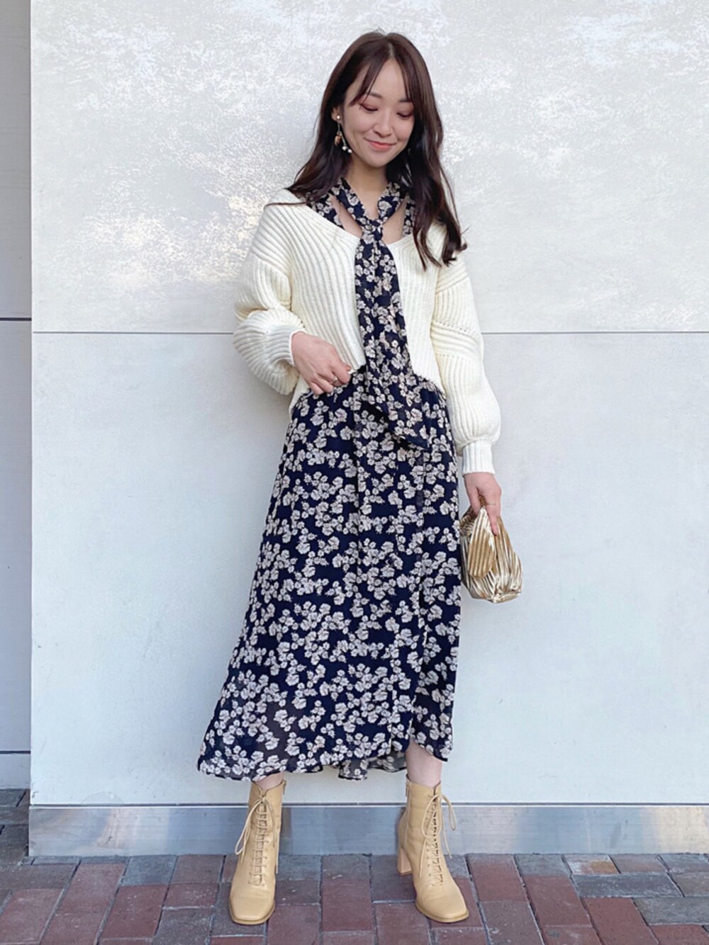 ベージュ系のクラッチバッグを着用したレディースの秋コーディネートの1枚目の写真