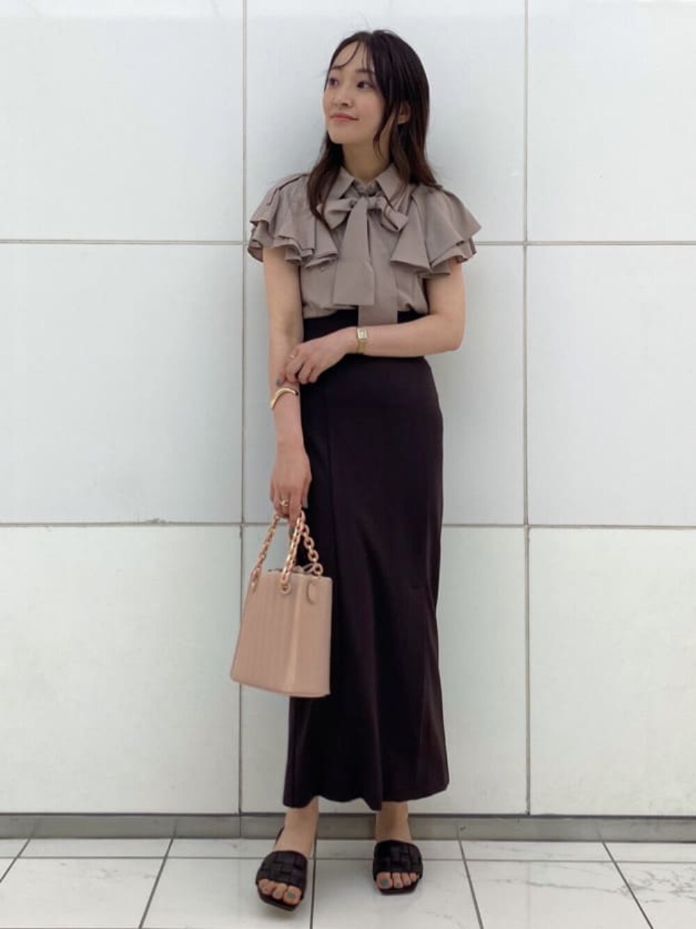 ピンク系のハンドバッグ、ブラウン系のサンダル、ベージュ系のシャツ/ブラウスを着用したレディースの夏コーディネートの1枚目の写真