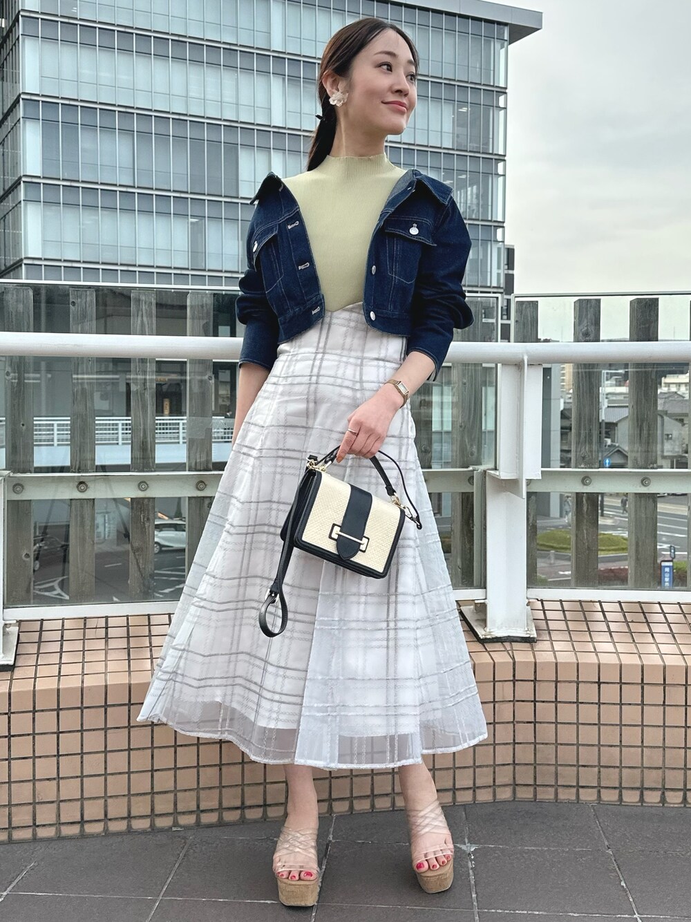 ホワイト系のハンドバッグ、グリーン系のワンピース、ブルー系のデニムジャケットを着用したレディースの春コーディネートの1枚目の写真