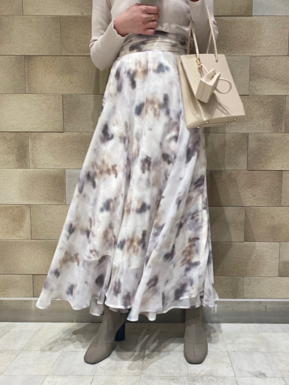 ベージュ系のトレンチコート、ベージュ系のトートバッグ、ホワイト系のニット/セーターを着用したレディースの冬コーディネートの1枚目の写真