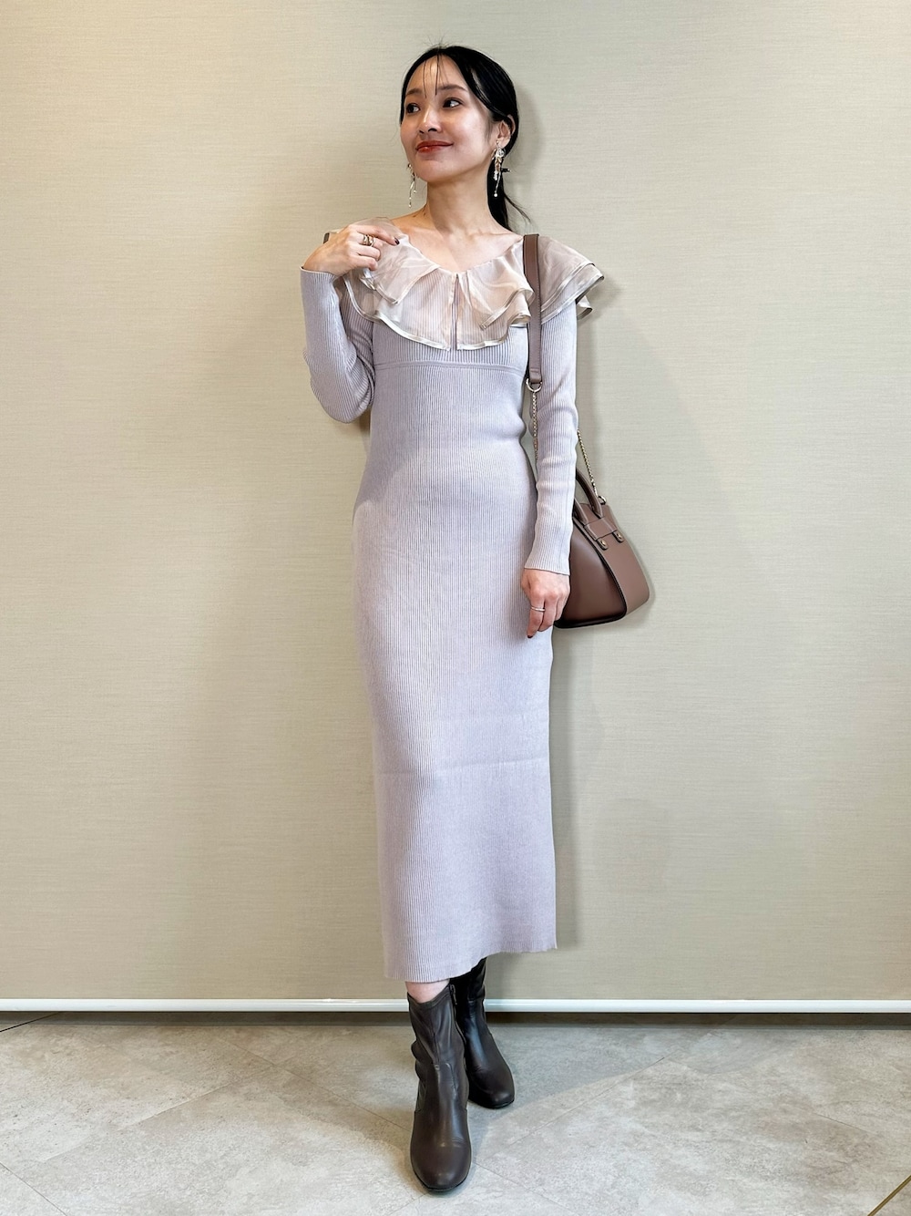 ブラウン系のブーツ、ブラウン系のハンドバッグ、ピンク系のワンピースを着用したレディースの冬コーディネートの1枚目の写真