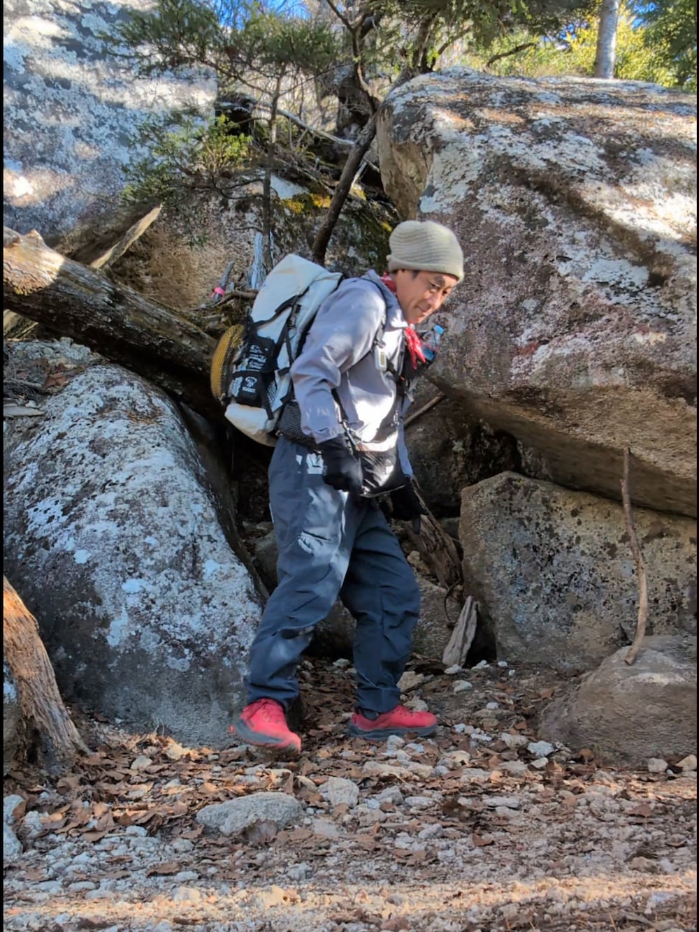 グレー系のマウンテンパーカー、ブルー系のパンツ、ホワイト系のバックパック/リュックを着用したメンズの秋コーディネートの1枚目の写真