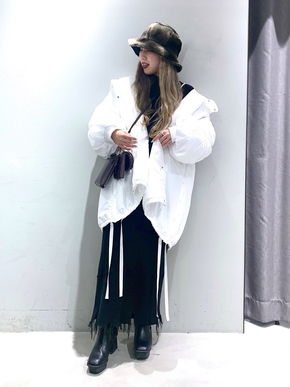 ホワイト系のブルゾン、グリーン系のニット/セーター、ブラック系のスカートを着用したレディースの冬コーディネートの4枚目の写真