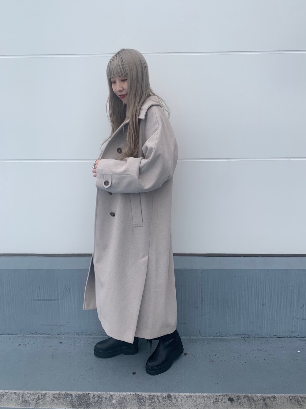 ブラック系のスラックス、ブラック系のブーツ、ホワイト系のニット/セーターを着用したレディースの冬コーディネートの2枚目の写真