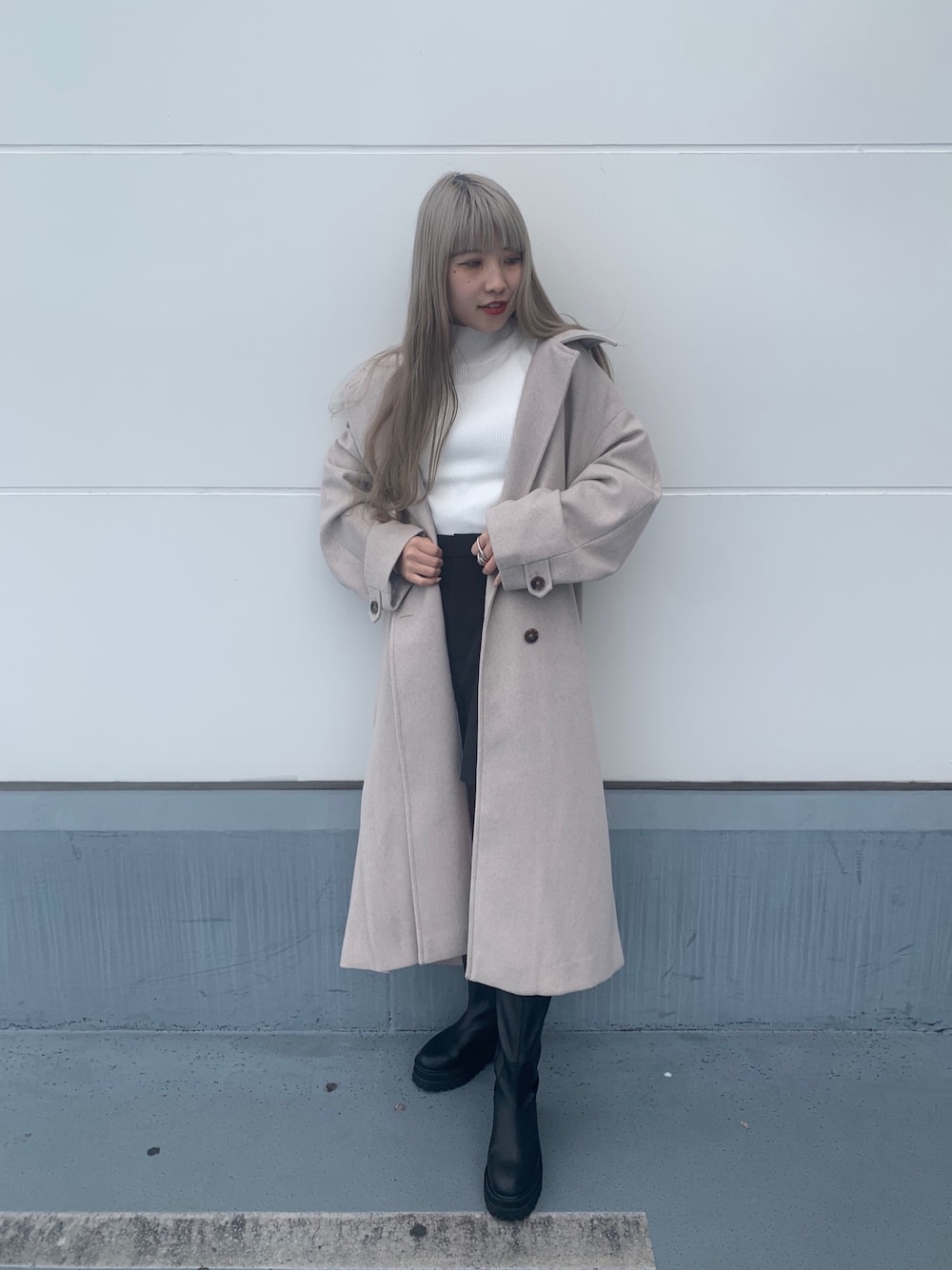 ブラック系のスラックス、ブラック系のブーツ、ホワイト系のニット/セーターを着用したレディースの冬コーディネートの3枚目の写真