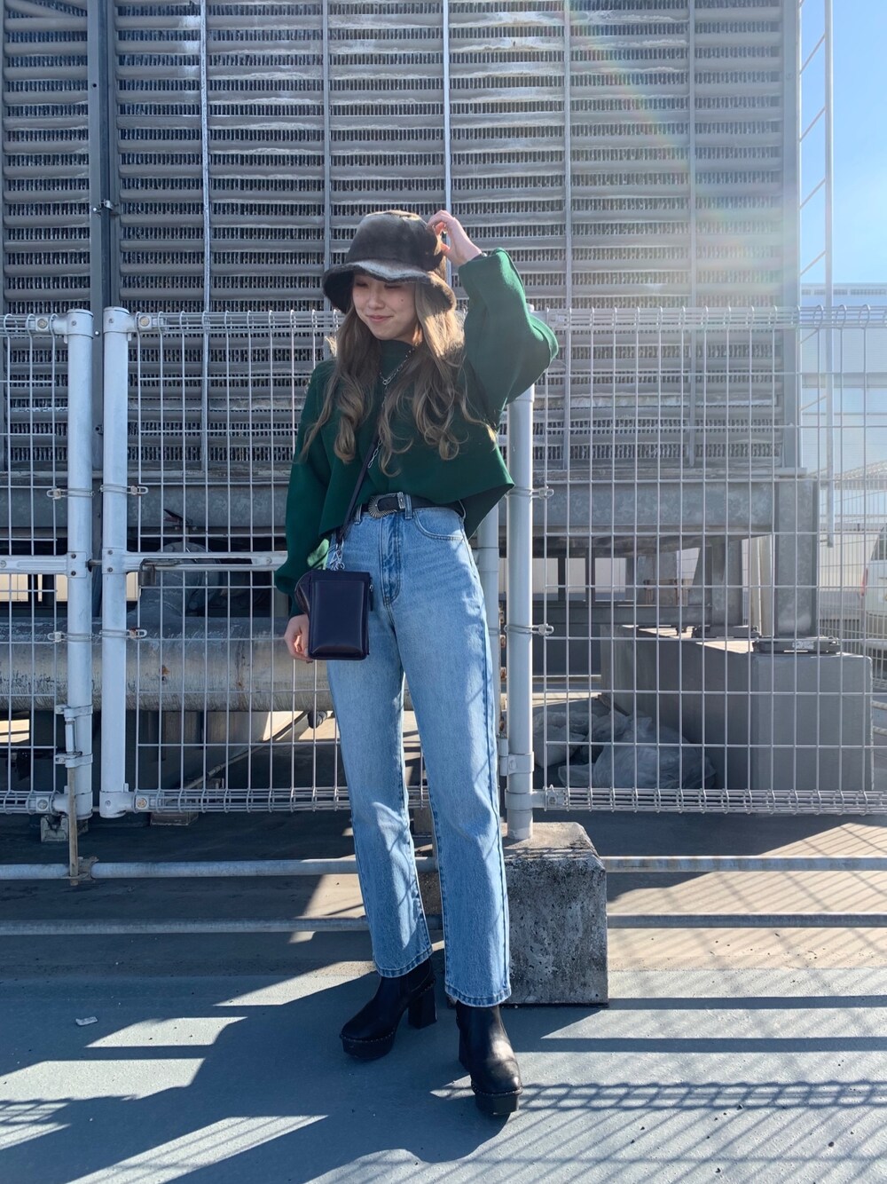 グリーン系のニット/セーター、ブラウン系のショルダーバッグ、ブラック系のベルトを着用したレディースの冬コーディネートの2枚目の写真