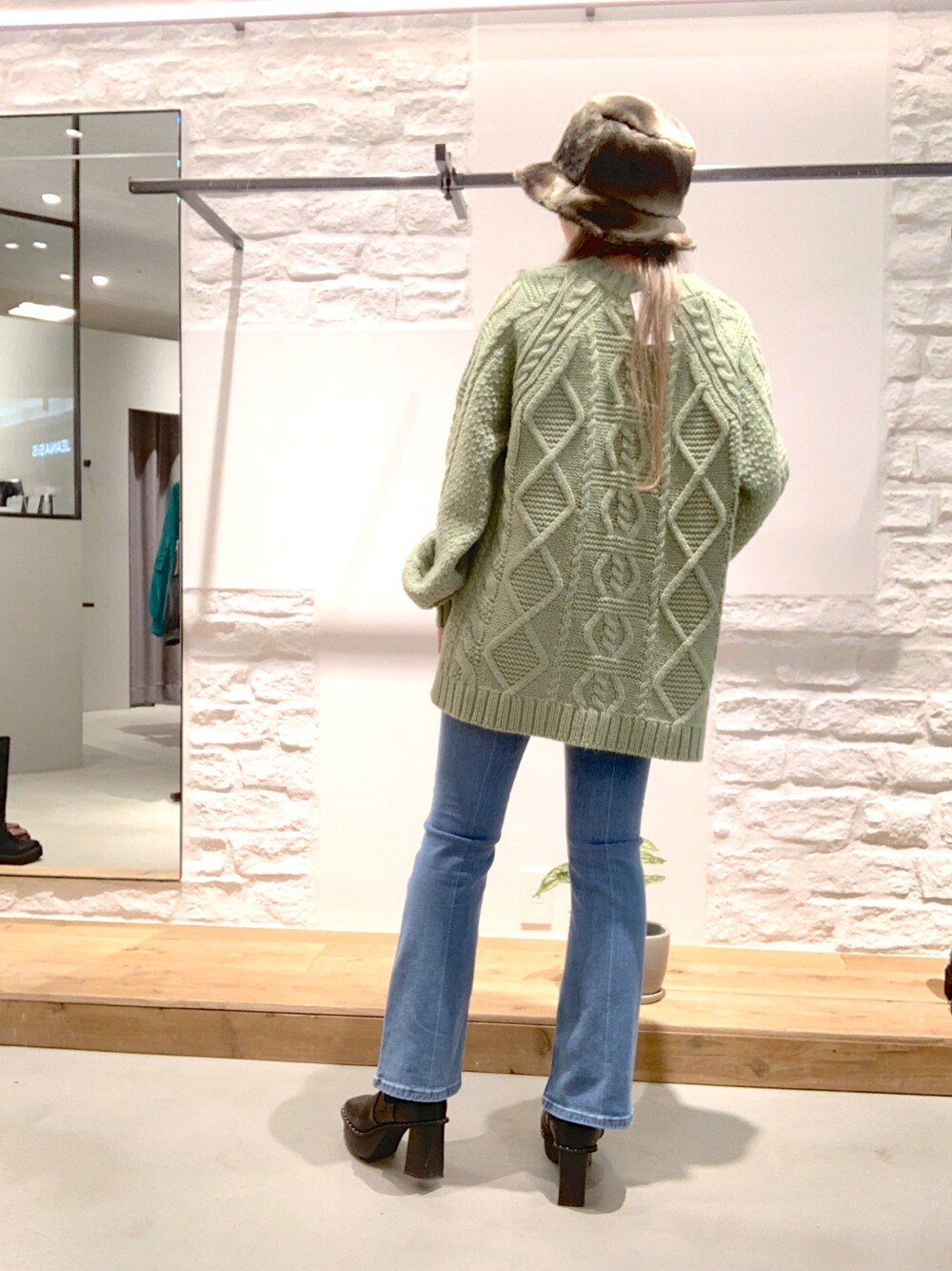 ブラック系のブーツ、ブルー系のデニムパンツ、グリーン系のニット/セーターを着用したレディースの冬コーディネートの3枚目の写真