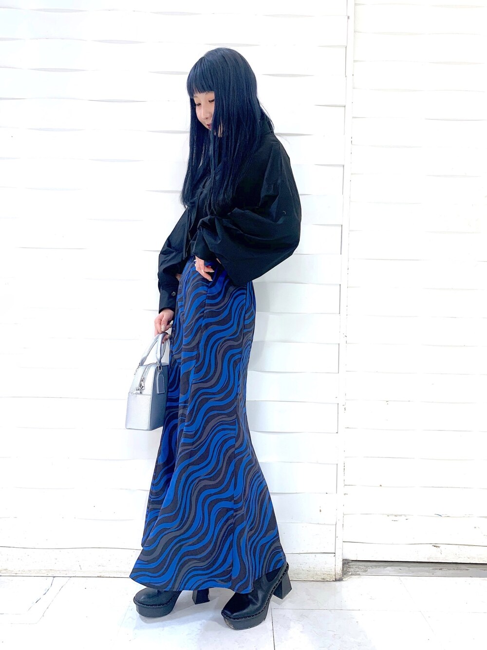 ホワイト系のスカート、シルバー系のショルダーバッグ、ブラック系のトップスを着用したレディースの冬コーディネートの4枚目の写真