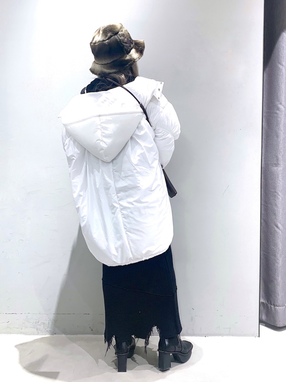 ホワイト系のブルゾン、グリーン系のニット/セーター、ブラック系のスカートを着用したレディースの冬コーディネートの2枚目の写真