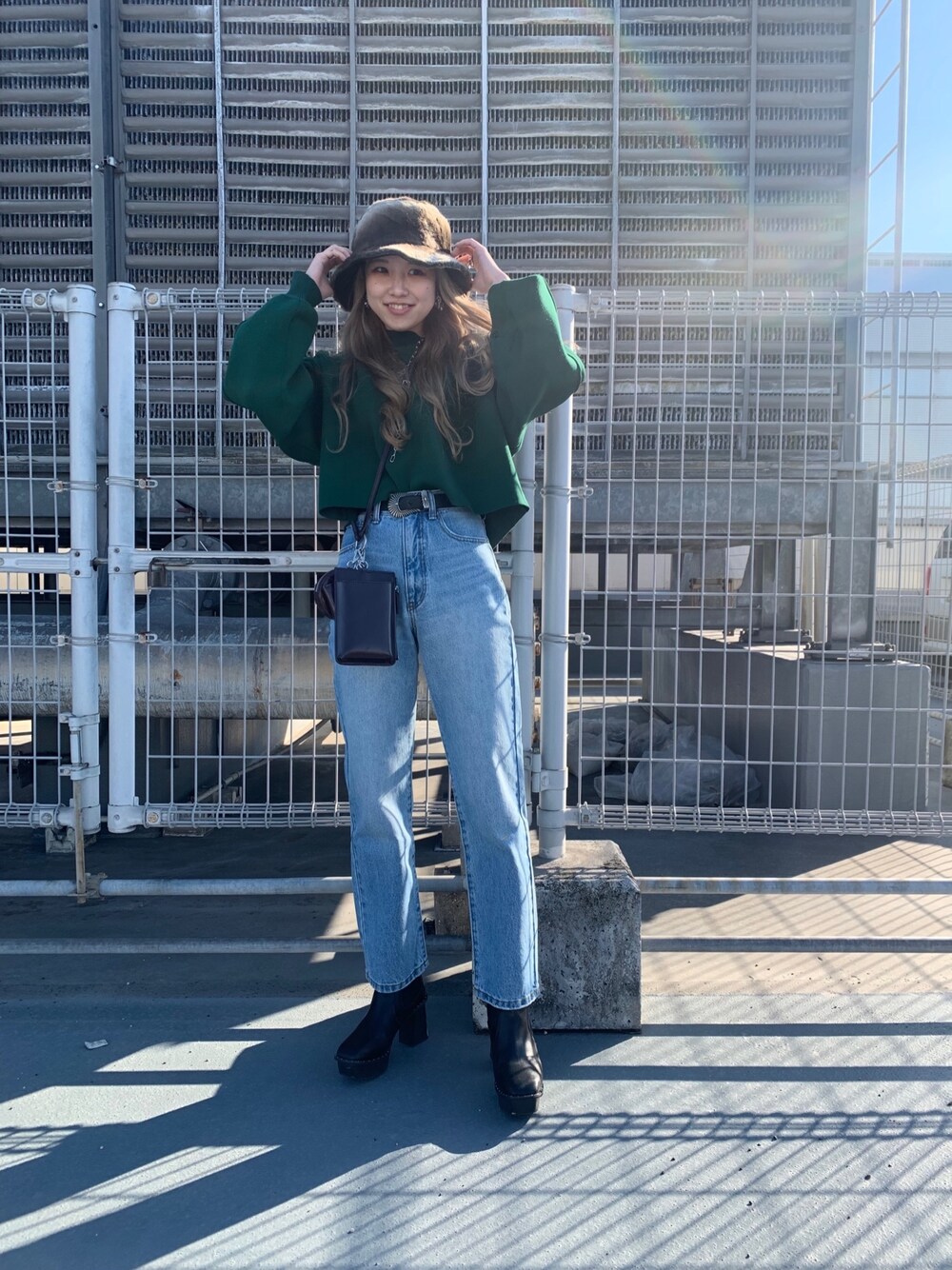 グリーン系のニット/セーター、ブラウン系のショルダーバッグ、ブラック系のベルトを着用したレディースの冬コーディネートの3枚目の写真