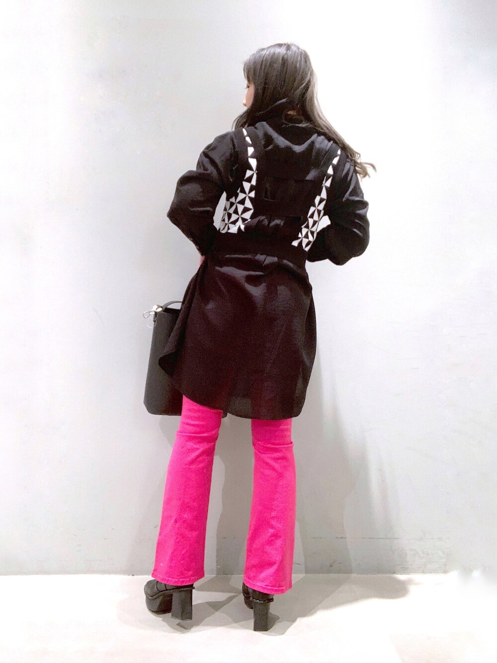 ブラック系のバッグ、ブラック系のブーツ、ピンク系のデニムパンツを着用したレディースの冬コーディネートの2枚目の写真