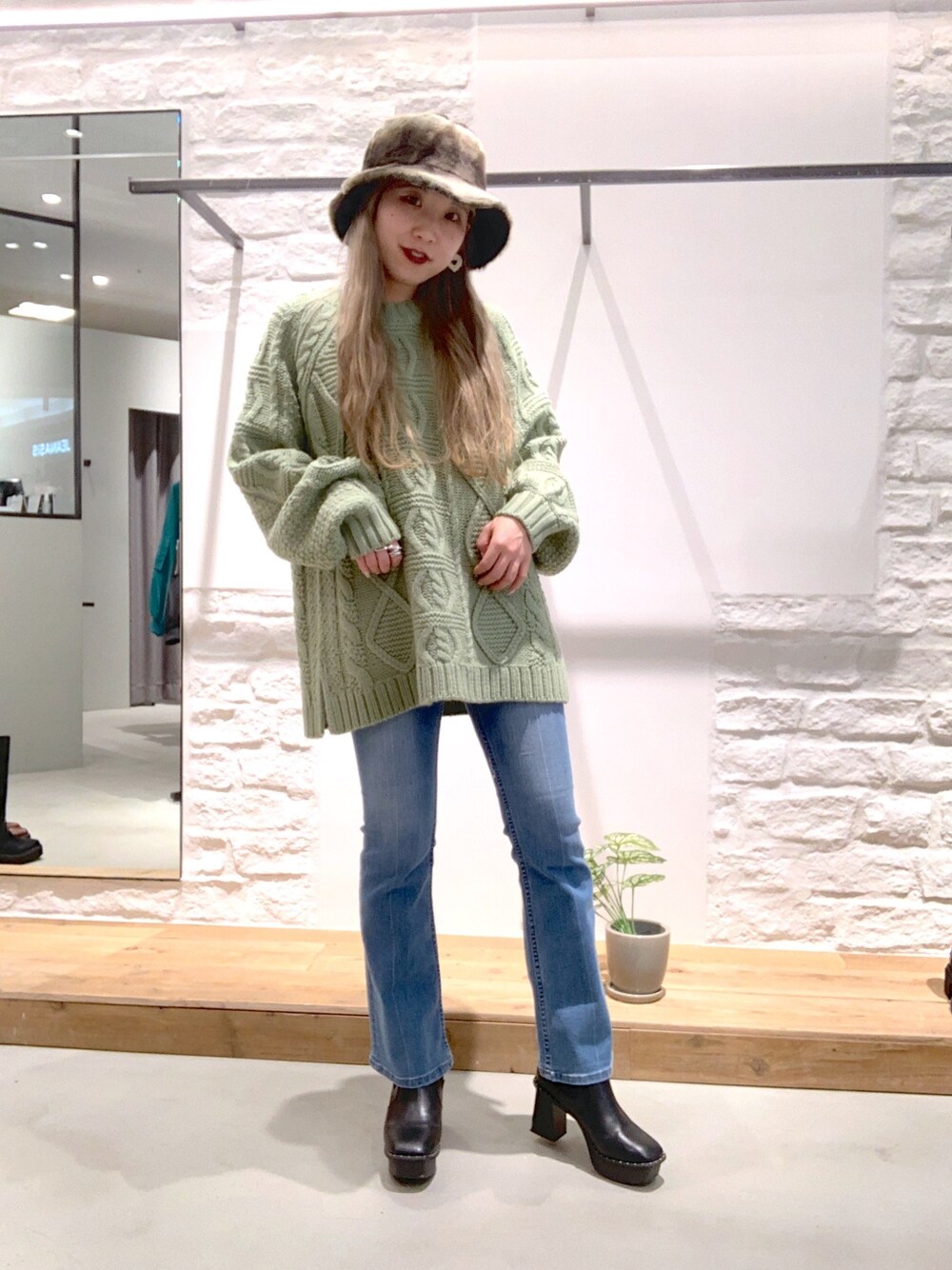 ブラック系のブーツ、ブルー系のデニムパンツ、グリーン系のニット/セーターを着用したレディースの冬コーディネートの2枚目の写真