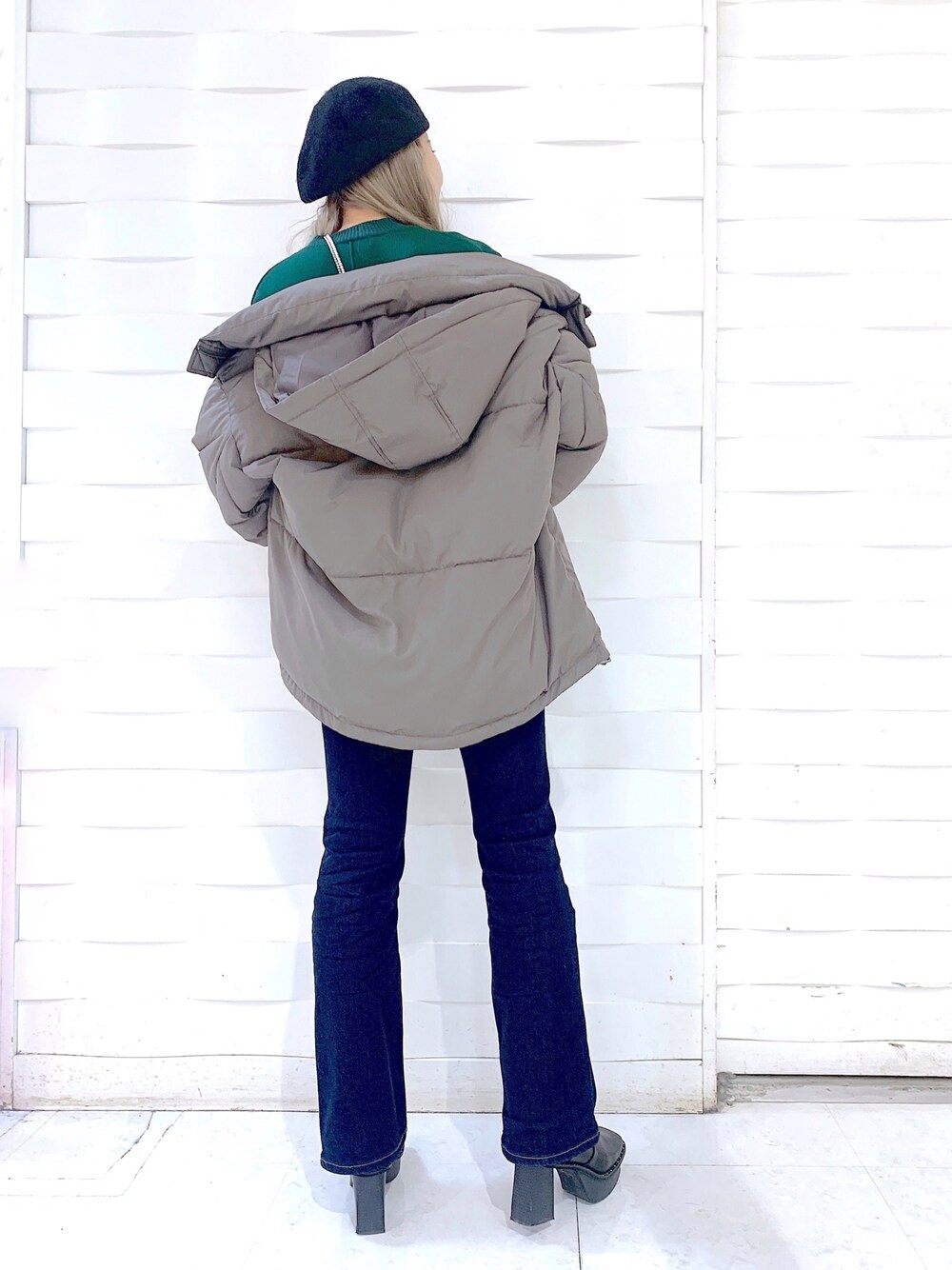 ブラック系のデニムパンツ、ブラック系のブーツ、グリーン系のニット/セーターを着用したレディースの冬コーディネートの2枚目の写真