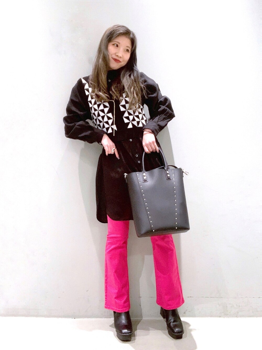 ブラック系のバッグ、ブラック系のブーツ、ピンク系のデニムパンツを着用したレディースの冬コーディネートの3枚目の写真