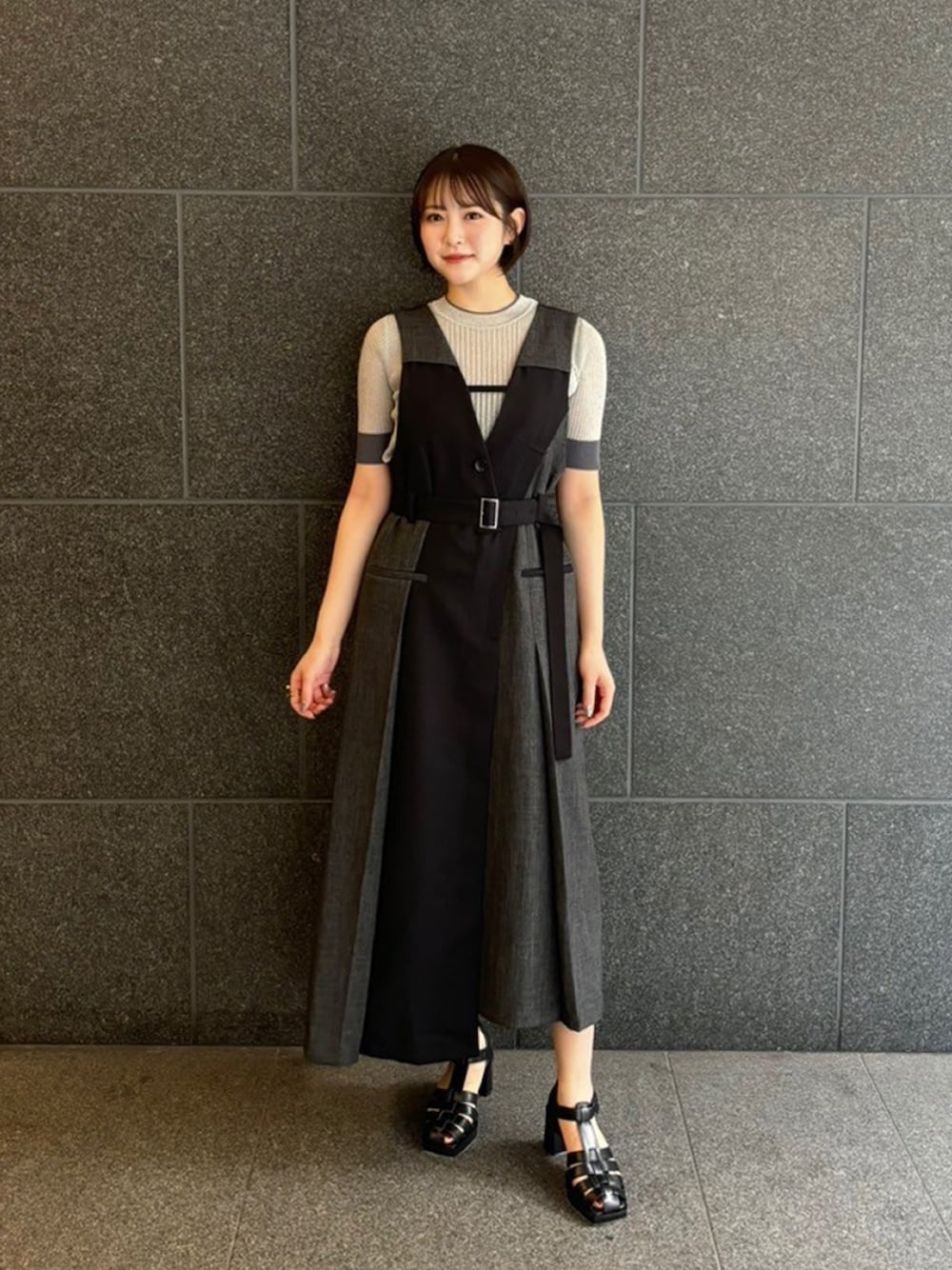 シルバー系のニット/セーター、ブラック系のジャンパースカートを着用したレディースの夏コーディネートの1枚目の写真