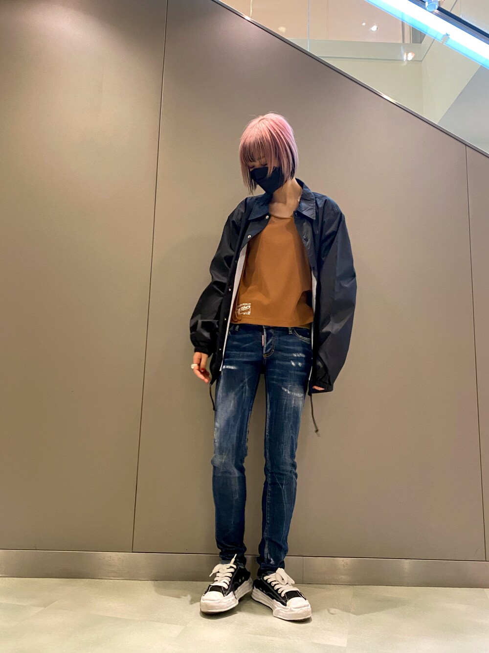 ブルー系のデニムパンツ、ブラック系のシューズ、オレンジ系のトップスを着用したレディースの冬コーディネートの1枚目の写真