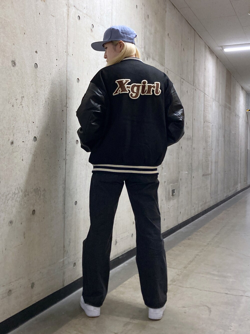 ブラック系のスタジャン、ブラック系のデニムパンツ、ブルー系のキャップを着用したレディースの秋コーディネートの1枚目の写真