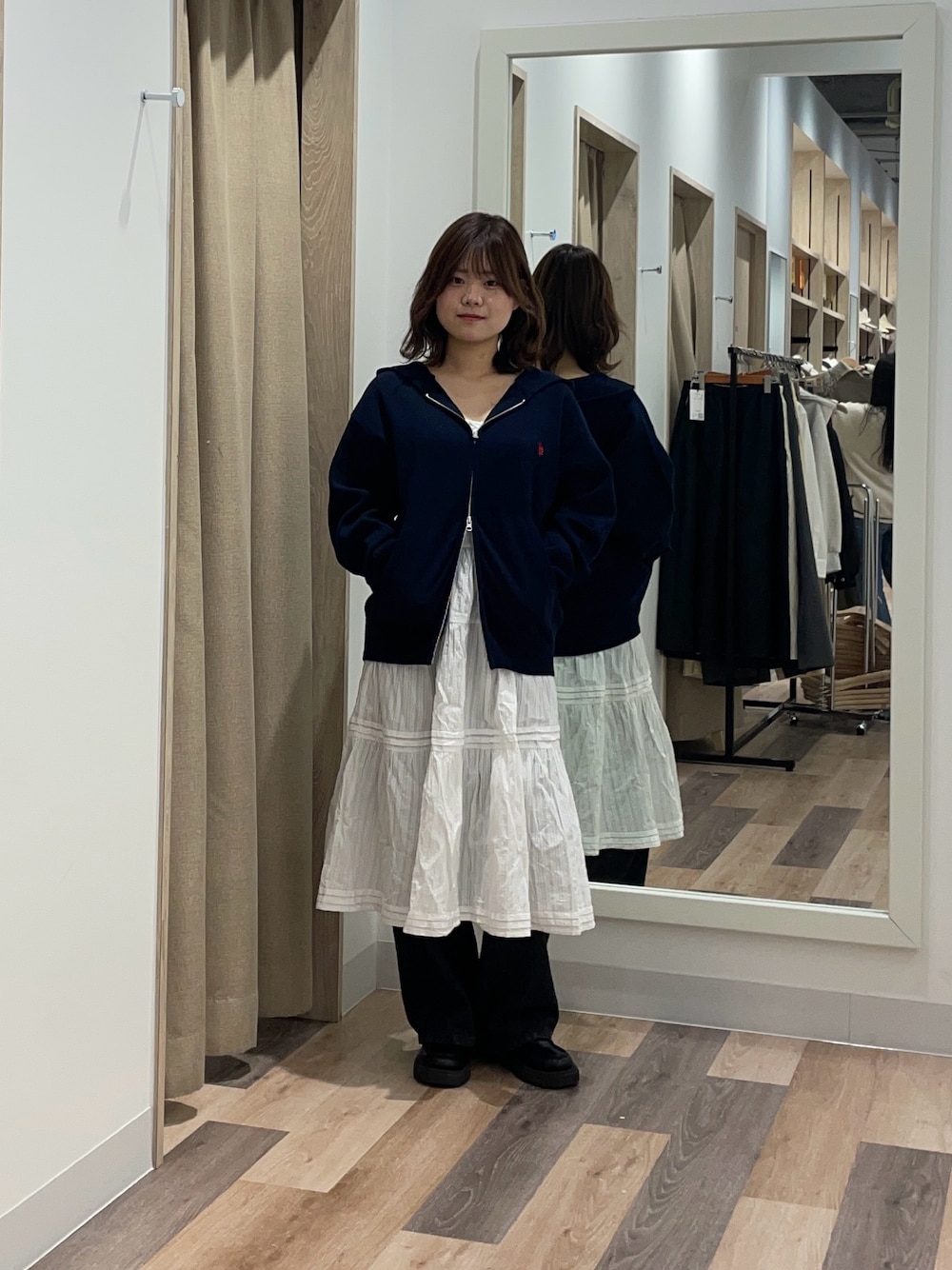 グレー系のニット/セーター、ホワイト系のスカート、ブラック系のデニムパンツを着用したレディースの冬コーディネートの1枚目の写真