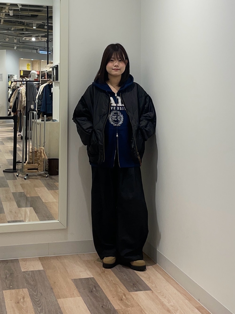 ブラック系のブルゾン、ブルー系のパーカー、ブラック系のスラックスを着用したレディースの冬コーディネートの1枚目の写真