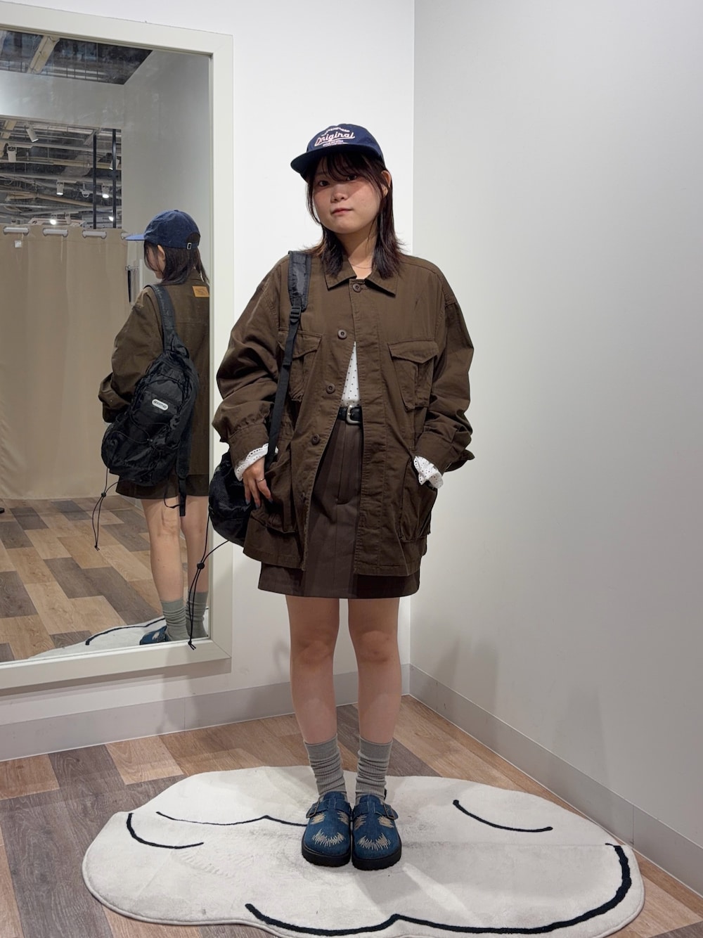 ブラック系のバックパック/リュック、ブラウン系のミリタリージャケット、ホワイト系のTシャツ/カットソーを着用したレディースの秋コーディネートの1枚目の写真