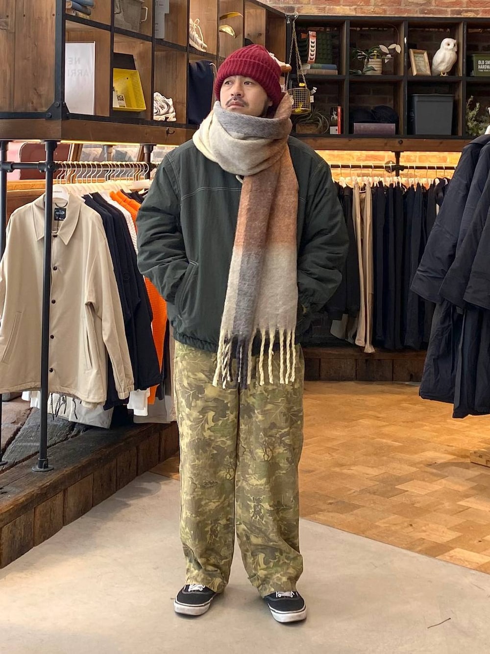 グリーン系のブルゾン、ベージュ系のその他パンツ、イエロー系のマフラーを着用したメンズの秋コーディネートの1枚目の写真