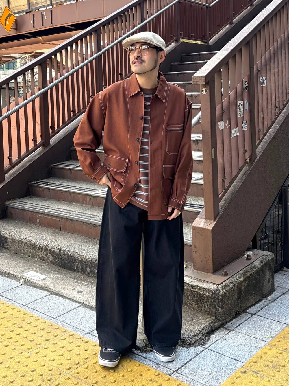 ブラウン系のカバーオール、ブラウン系のTシャツ/カットソー、ブラック系のデニムパンツを着用したメンズの春コーディネートの1枚目の写真