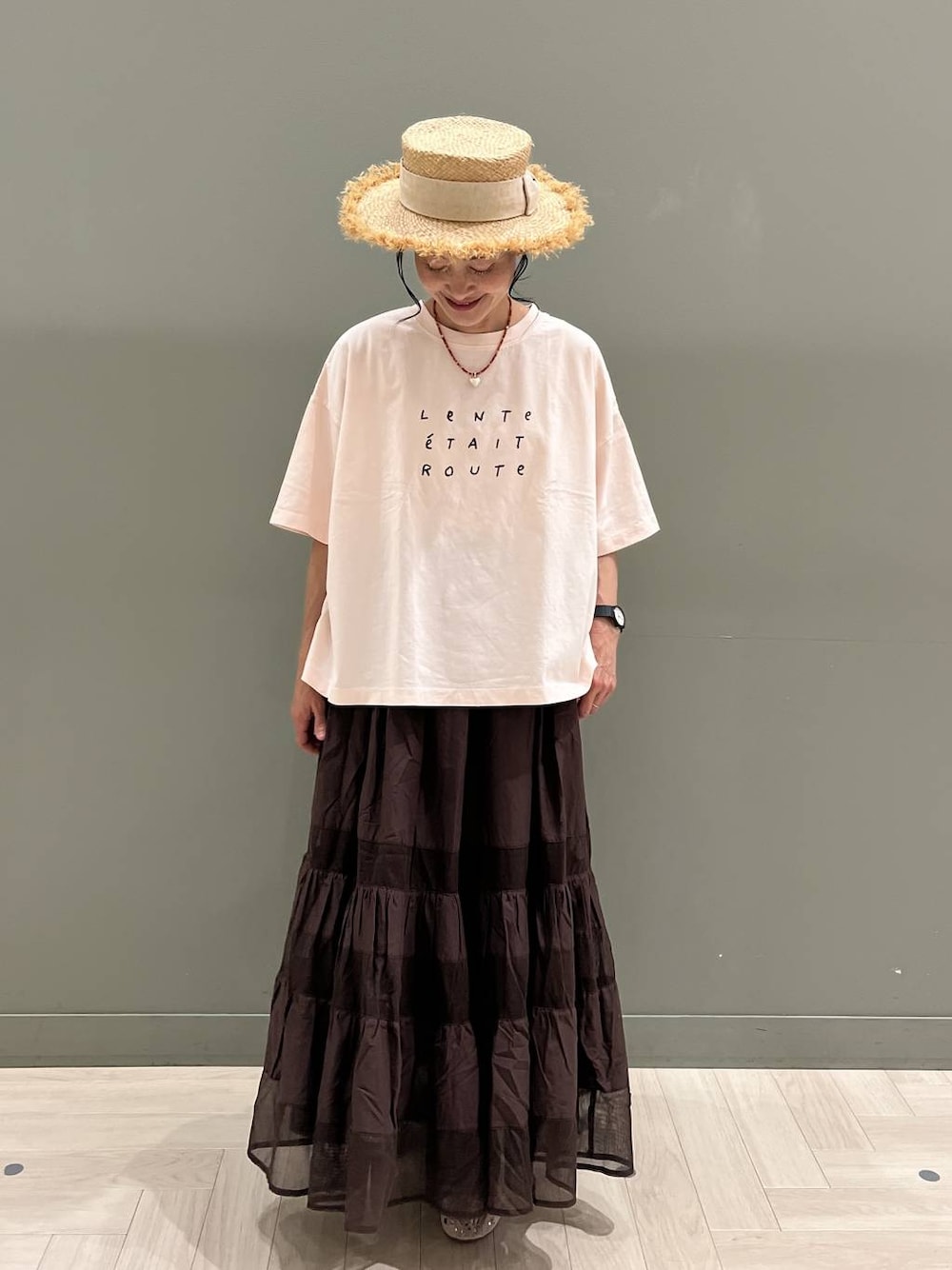 ブラック系のトートバッグ、ピンク系のTシャツ/カットソー、ブラウン系のスカートを着用したレディースの夏コーディネートの1枚目の写真