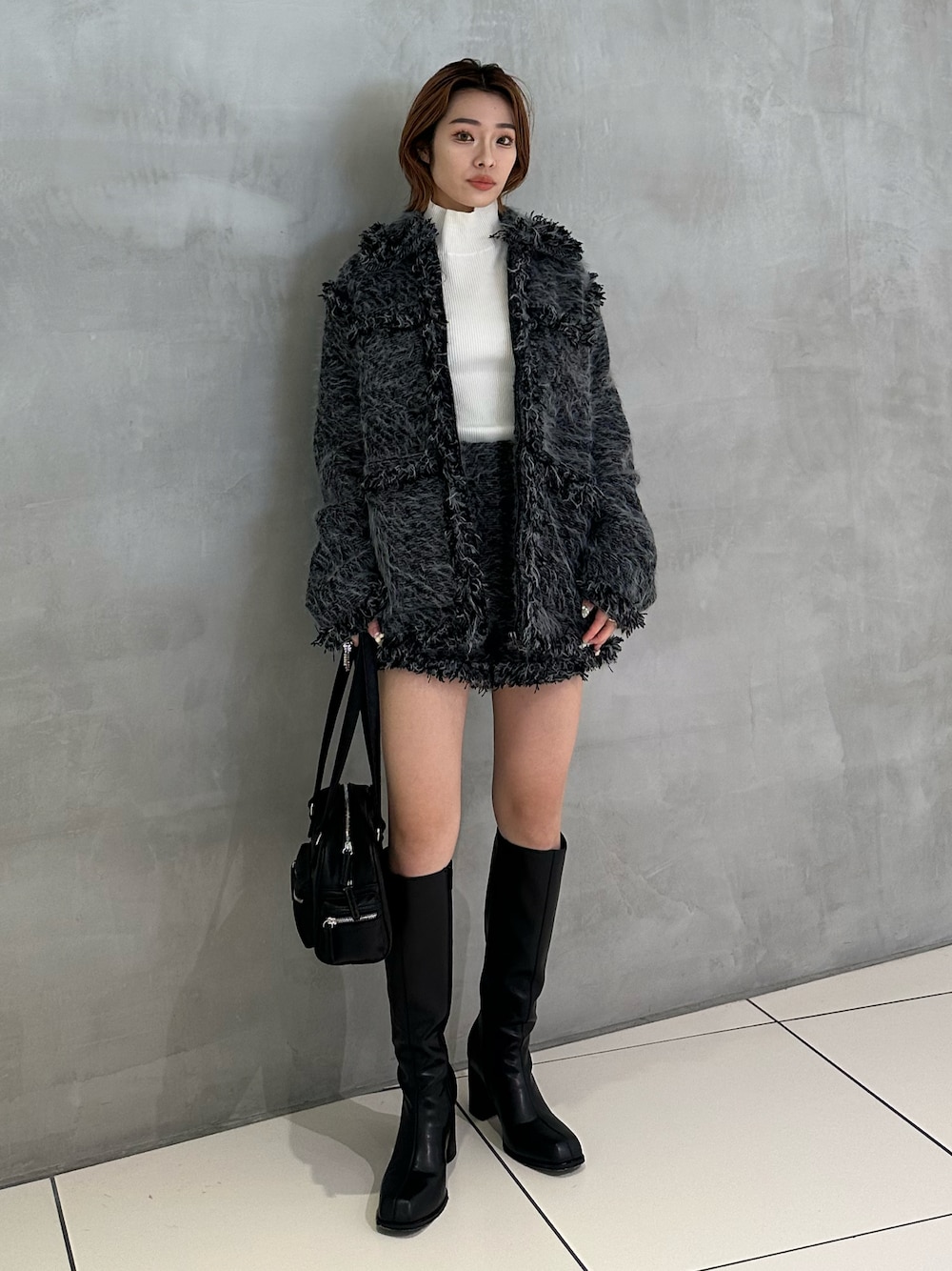 ホワイト系のニット/セーター、ブラック系のショルダーバッグ、ブラック系のブーツを着用したレディースの冬コーディネートの1枚目の写真