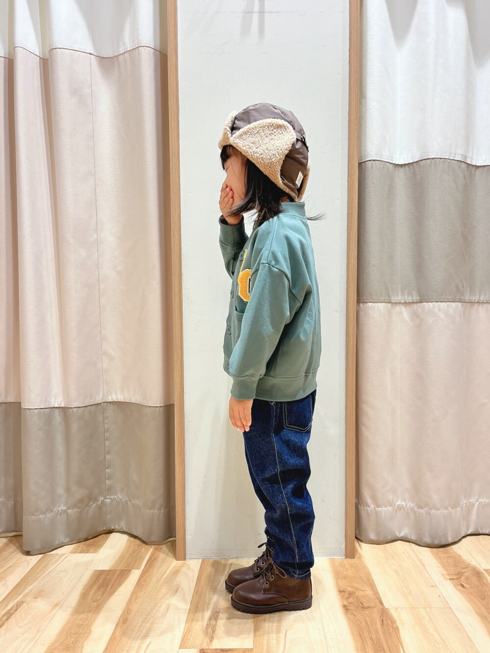 グリーン系のカーディガン/ボレロ、ブルー系のデニムパンツ、ブラウン系のブーツを着用したレディースの秋コーディネートの1枚目の写真