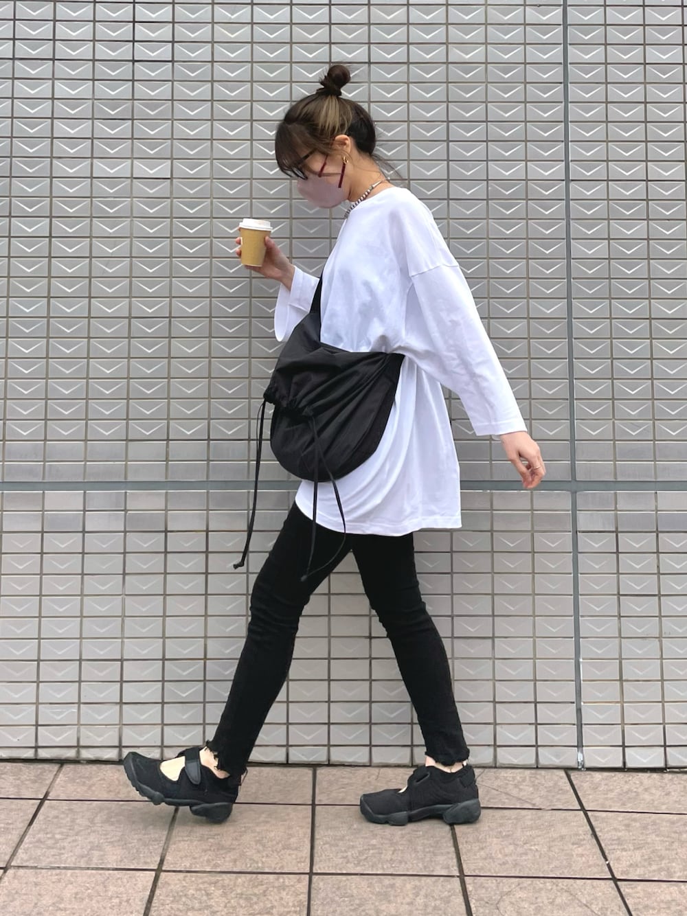 ブラック系のバッグ、ブラック系のサンダル、ホワイト系のTシャツ/カットソーを着用したレディースの春コーディネートの1枚目の写真
